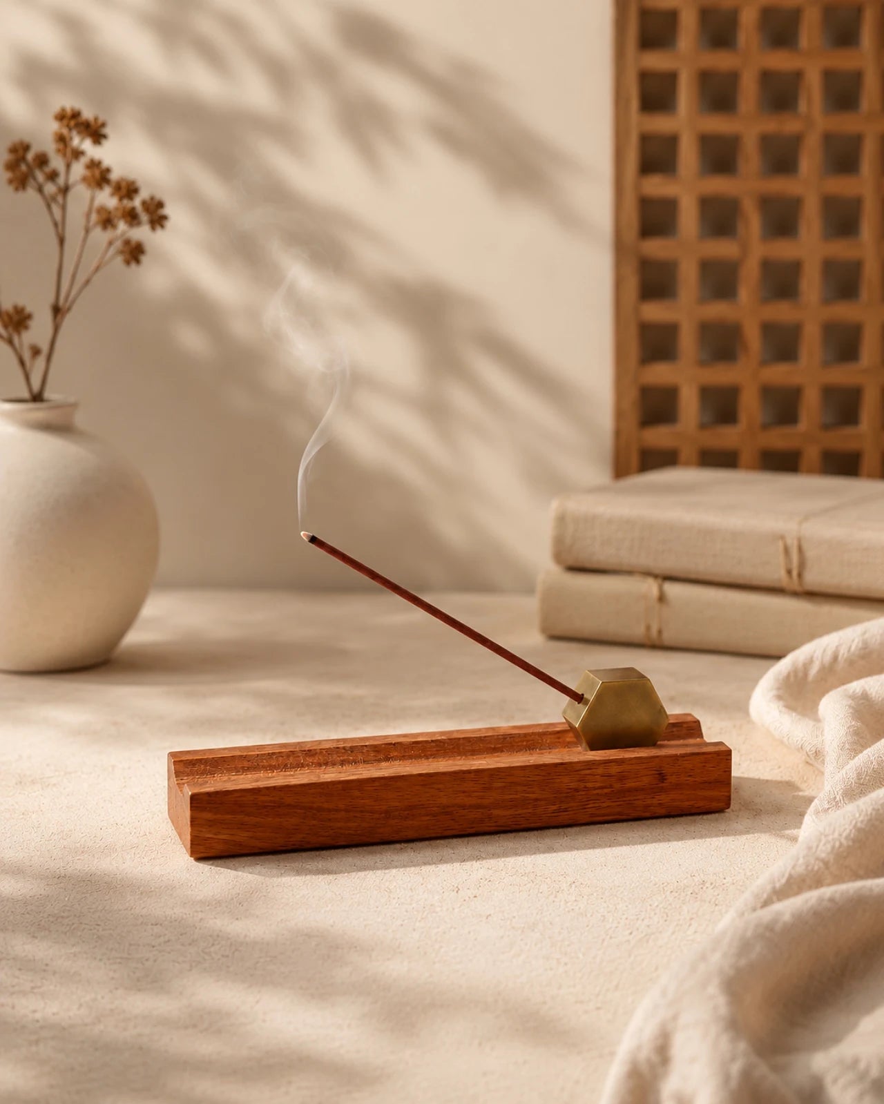 Porta incenso artigianale in legno di acacia ed ottone con bastoncino sottile giapponese acceso in diagonale: il fumo sale lentamente in atmosfera calda e naturale