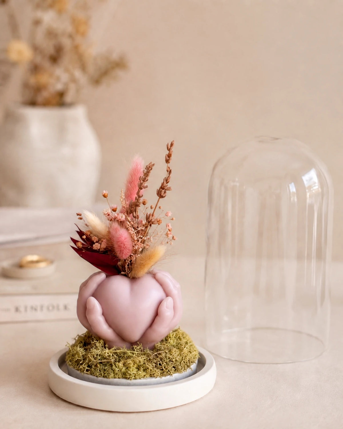 Carinho: composizione di fiori secchi in vaso di cera a forma di cuore sorretto da mani con campana di vetro e base di legno - Io Sono La Luce Roma | Colore rosa cipria antico