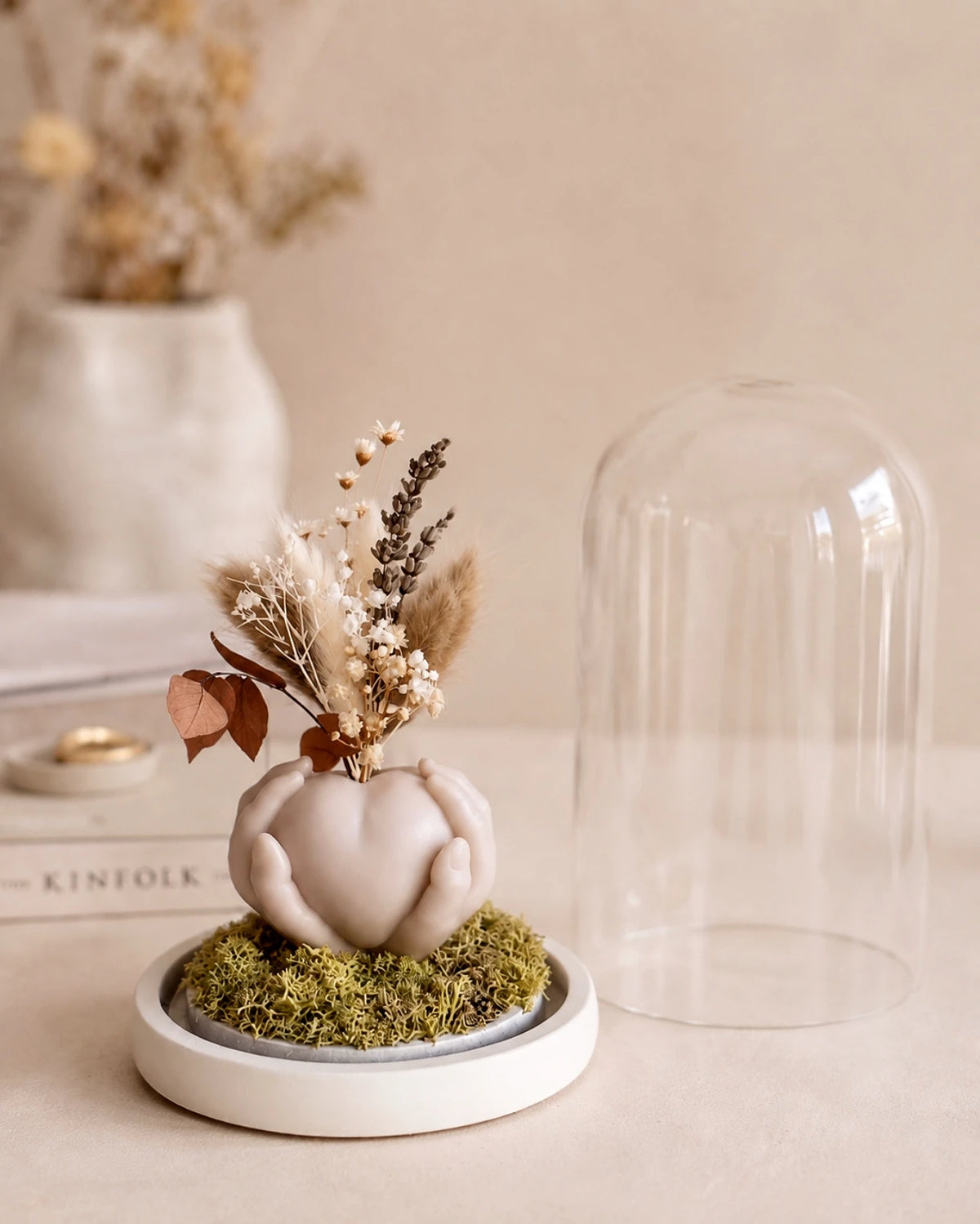 Carinho: composizione di fiori secchi in vaso di cera a forma di cuore sorretto da mani con campana di vetro e base di legno - Io Sono La Luce Roma | Colore sabbia