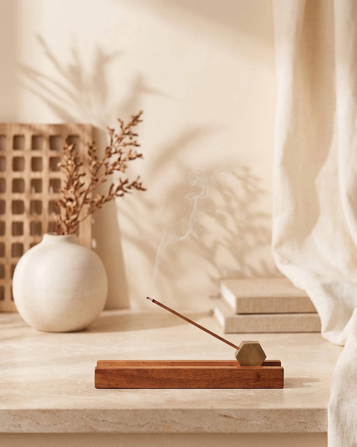Porta incenso artigianale in legno di acacia ed ottone con bastoncino sottile giapponese acceso in diagonale: idea regalo slow living per rituali quotidiani